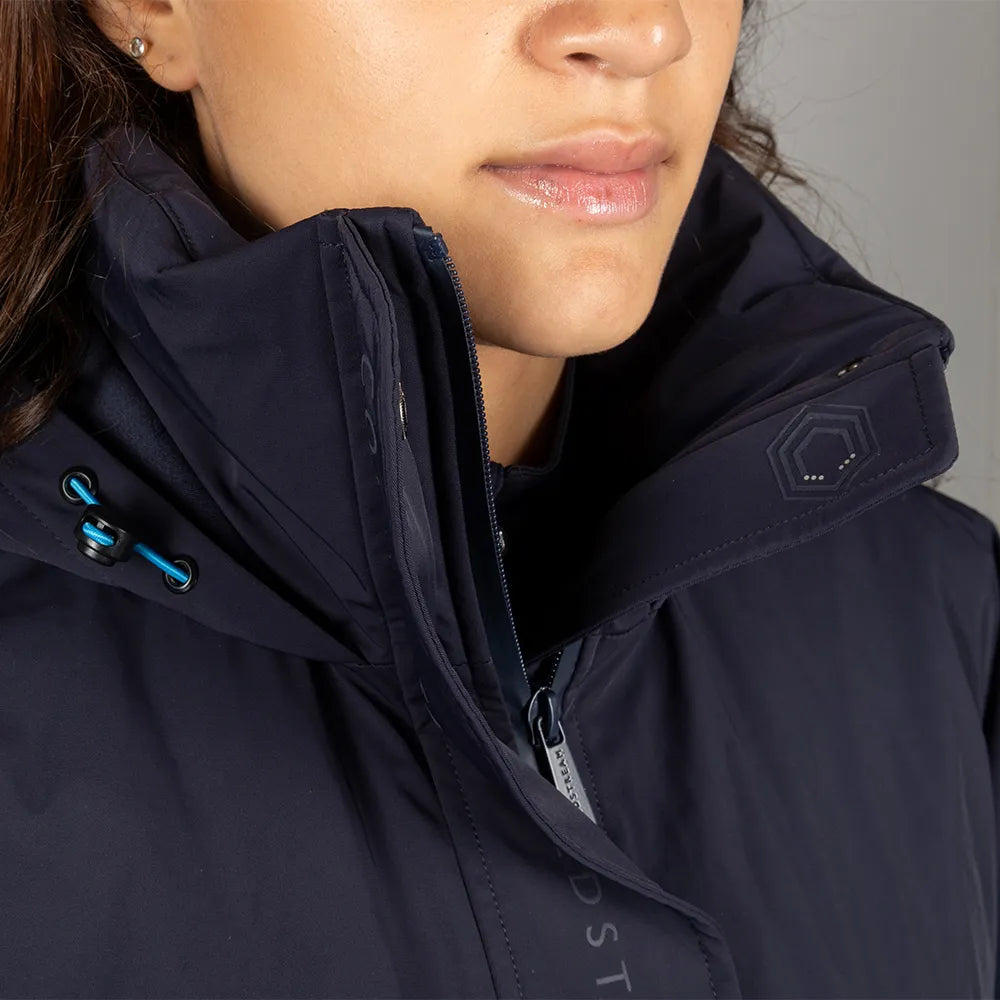 Close-up of a person wearing a navy blue jacket with a brand logo on a gray background